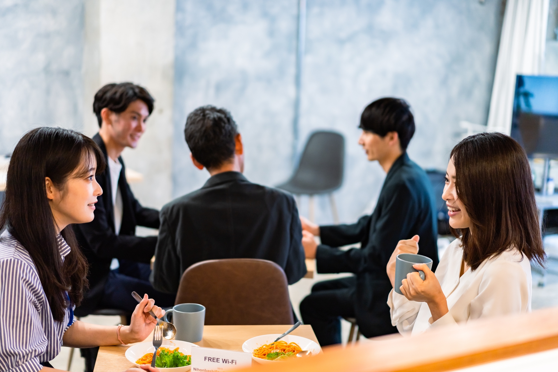 社員食堂で食事をしながら話す女性