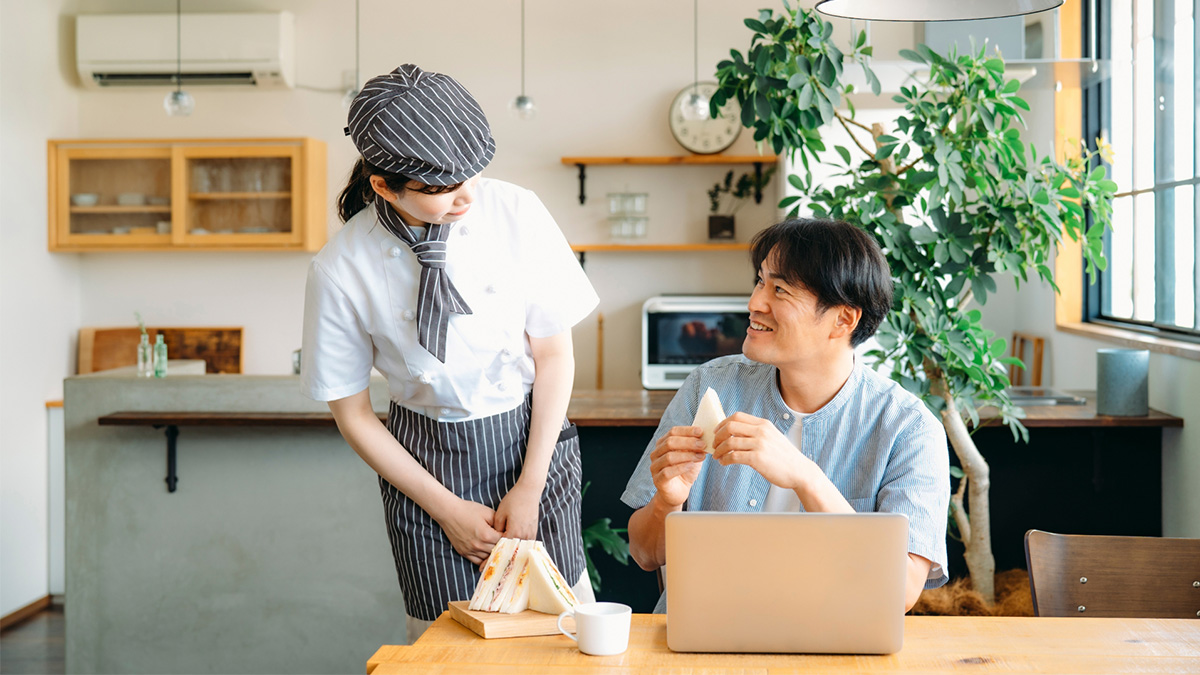 食堂で社員が食事をしながら給食委託業者と話す様子